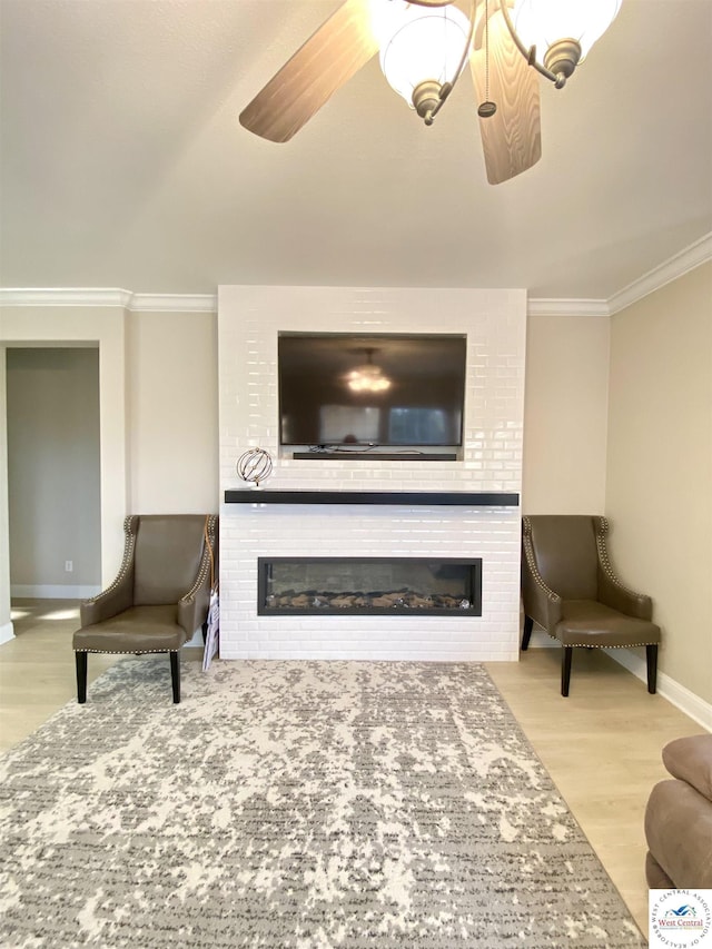 living area featuring a fireplace, wood finished floors, baseboards, and ornamental molding