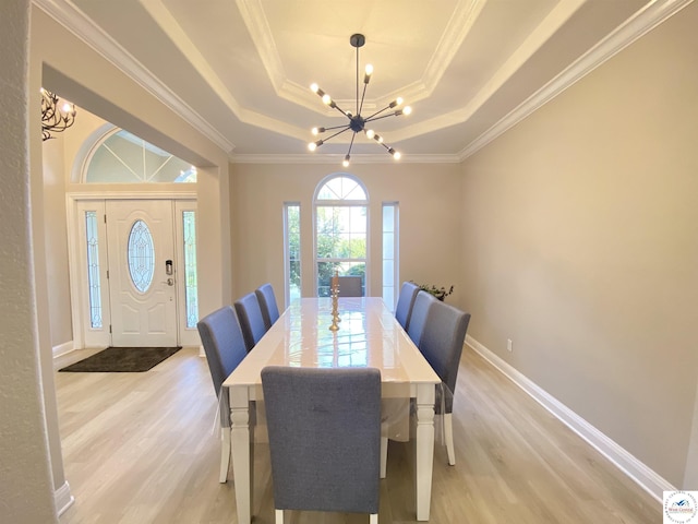 dining area with an inviting chandelier, baseboards, light wood-type flooring, crown molding, and a tray ceiling