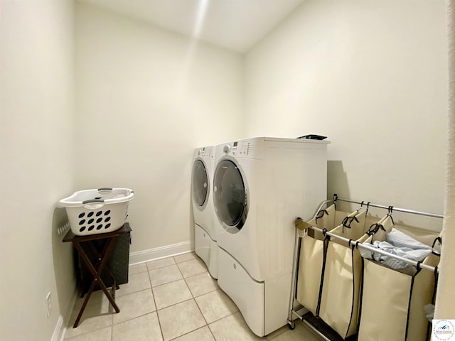 clothes washing area featuring baseboards, washer and dryer, laundry area, and light tile patterned floors