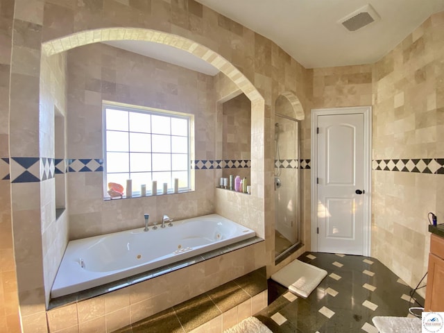 full bathroom featuring tile walls, visible vents, a shower stall, and a tub with jets