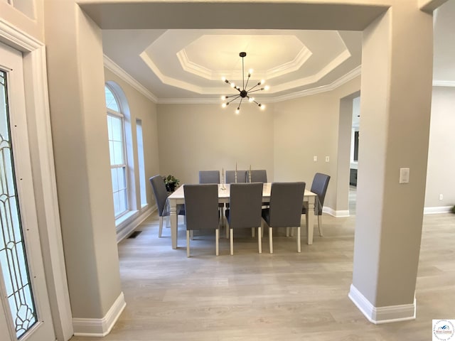 dining space featuring crown molding, light wood-type flooring, a tray ceiling, baseboards, and a notable chandelier