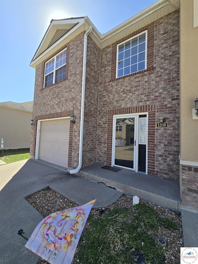 townhome / multi-family property featuring driveway, an attached garage, and brick siding