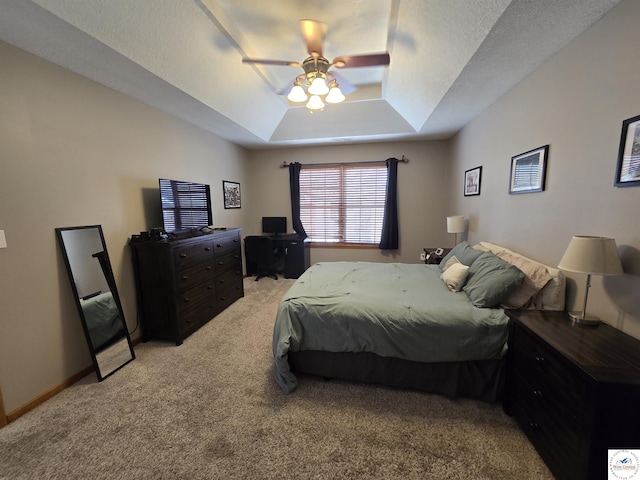 bedroom featuring a raised ceiling, ceiling fan, and light colored carpet