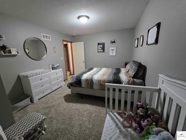 carpeted bedroom featuring a textured ceiling and visible vents