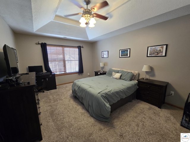 carpeted bedroom with a ceiling fan, a raised ceiling, and baseboards