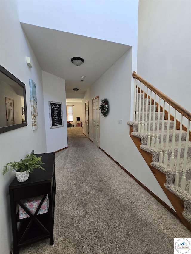 corridor featuring stairs, carpet, and baseboards