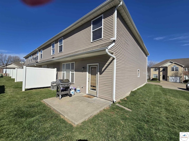 rear view of property featuring fence, a yard, and a patio area