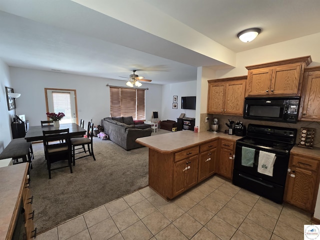 kitchen with brown cabinets, black appliances, open floor plan, light carpet, and a peninsula