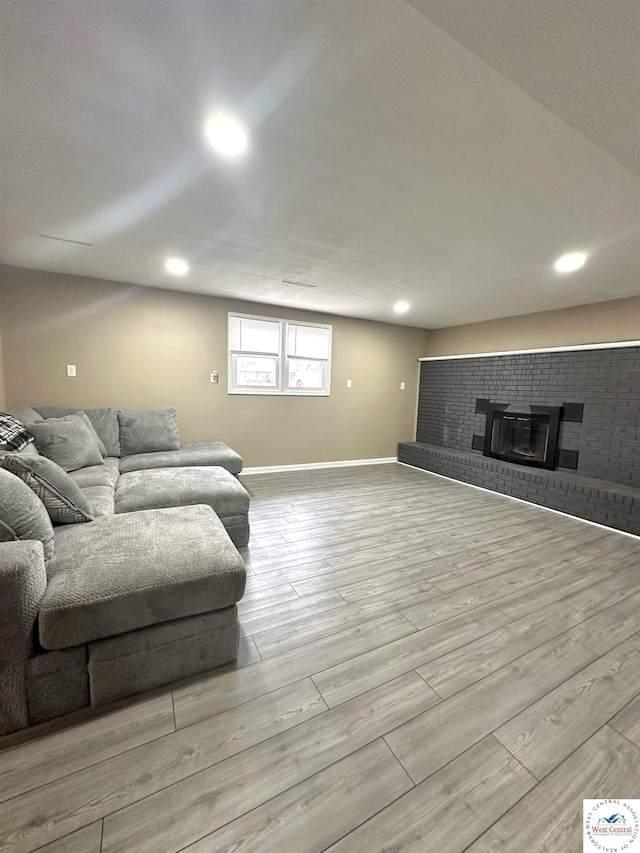 living area featuring a brick fireplace, recessed lighting, wood finished floors, and baseboards
