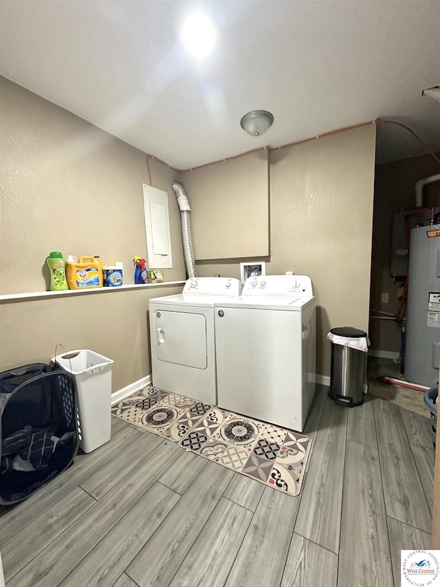 clothes washing area with washing machine and dryer, electric panel, laundry area, water heater, and wood finished floors