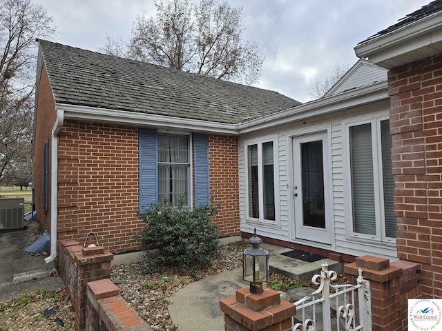 view of home's exterior with fence, central AC, and brick siding