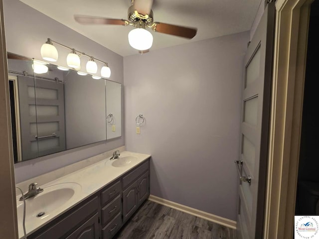bathroom featuring wood finished floors, a ceiling fan, double vanity, and a sink