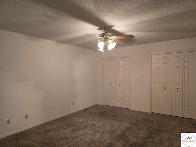 unfurnished bedroom with carpet floors, multiple closets, ceiling fan, baseboards, and a textured ceiling