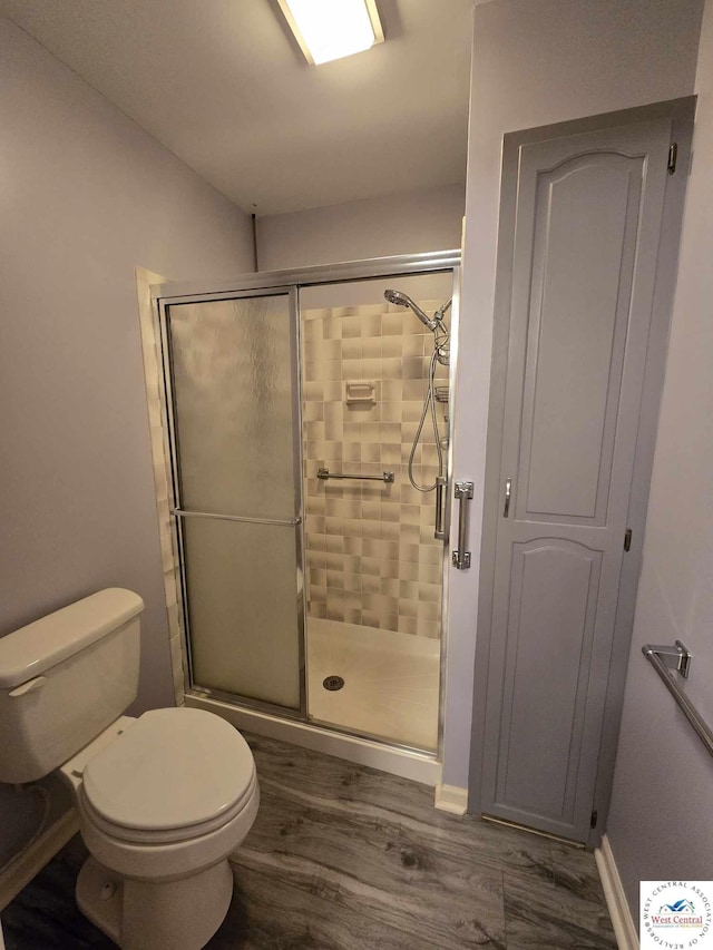 full bathroom featuring toilet, a stall shower, wood finished floors, and baseboards