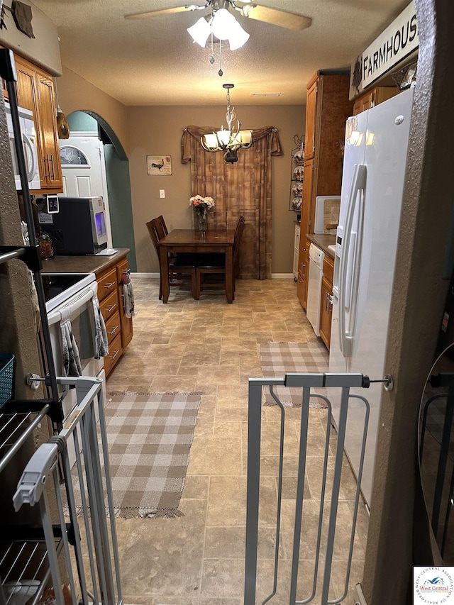 34443 Peters Ave, Warsaw, MO 65355 - kitchen featuring brown cabinetry, white appliances, ceiling fan with notable chandelier, and arched walkways