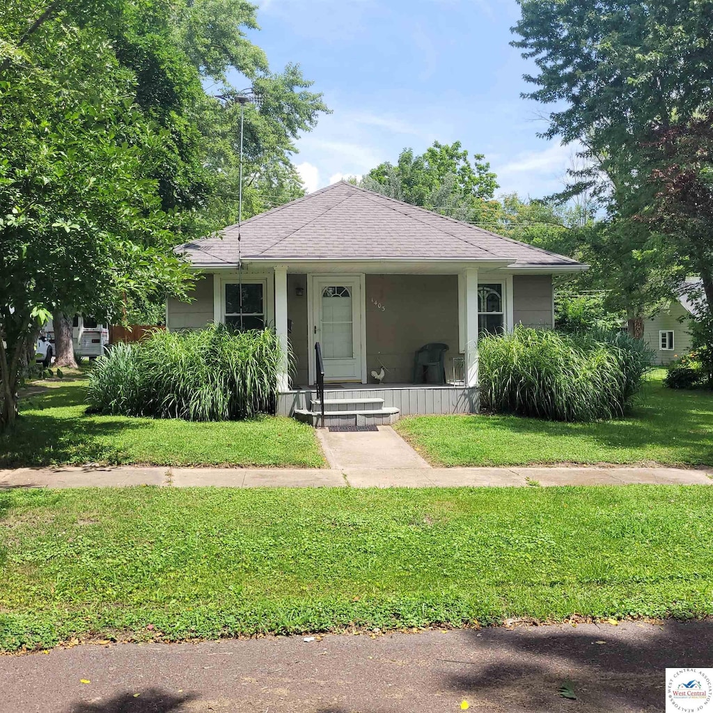 1403 E 10th St, Sedalia, MO 65301 - bungalow-style house with a front lawn, a porch, and roof with shingles