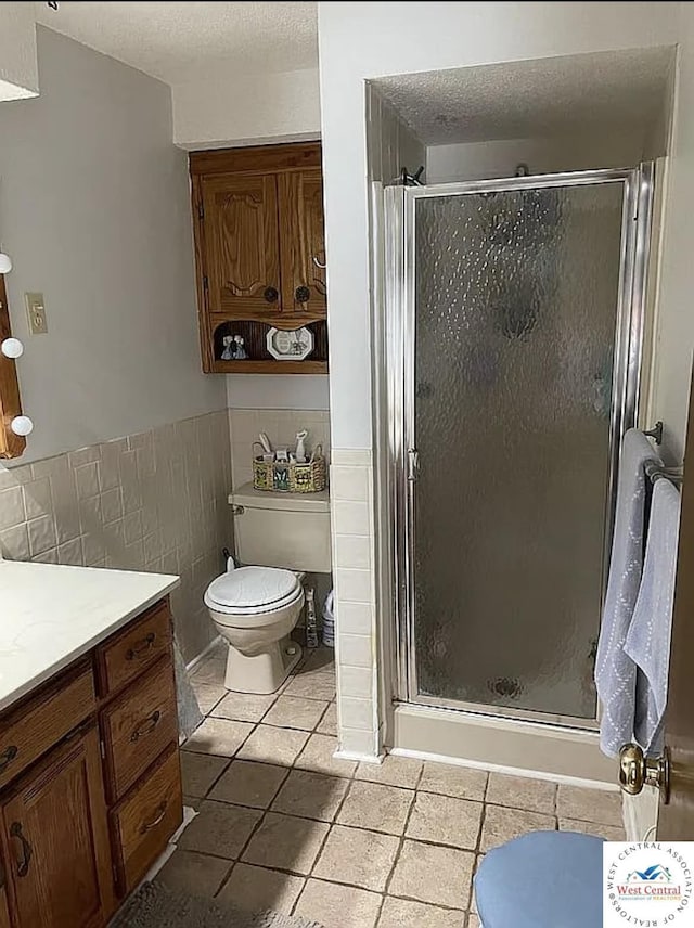 592 Woodland Dr, Climax Springs, MO 65324 - bathroom with tile patterned floors, tile walls, a stall shower, vanity, and wainscoting