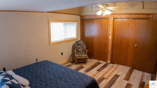 bedroom with baseboards, wood finished floors, ornamental molding, and multiple closets