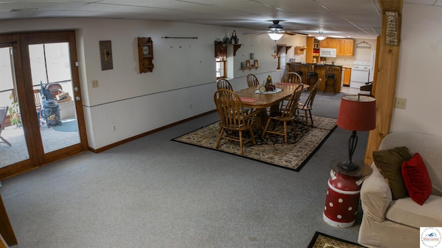 dining area featuring a wealth of natural light, light carpet, electric panel, and a drop ceiling