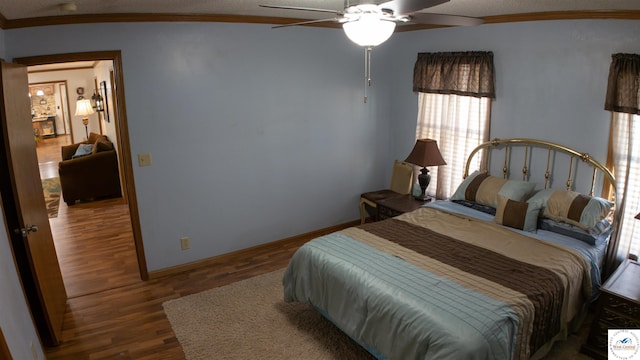 bedroom with baseboards, wood finished floors, ceiling fan, and crown molding