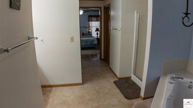 hallway featuring baseboards and light colored carpet