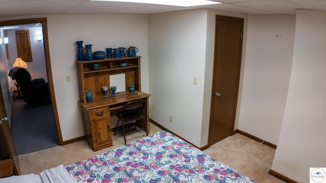 bedroom featuring baseboards, light carpet, and a paneled ceiling