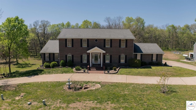 colonial-style house with concrete driveway, a front yard, and brick siding