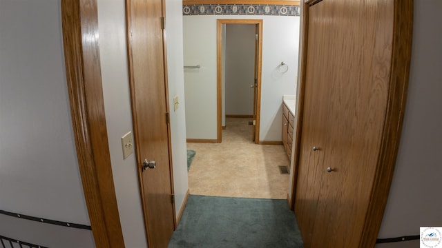corridor featuring baseboards and carpet floors