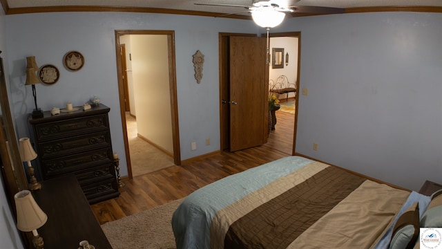 bedroom with wood finished floors, crown molding, a ceiling fan, and baseboards