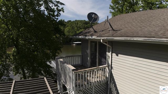 view of home's exterior with roof with shingles, stairway, and a deck with water view