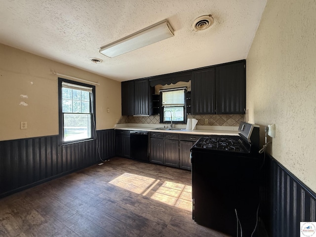 109 E Fairview St, Clinton, MO 64735 - kitchen with black dishwasher, a textured ceiling, a wainscoted wall, stainless steel range with gas stovetop, and plenty of natural light