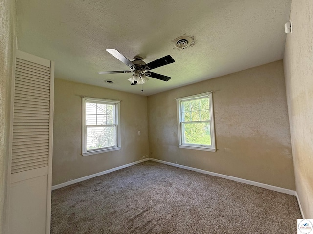 109 E Fairview St, Clinton, MO 64735 - unfurnished bedroom featuring multiple windows, a textured ceiling, carpet floors, a closet, and ceiling fan