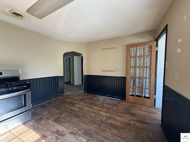 109 E Fairview St, Clinton, MO 64735 - kitchen featuring stainless steel range with gas cooktop, a wainscoted wall, wood finished floors, arched walkways, and a textured ceiling
