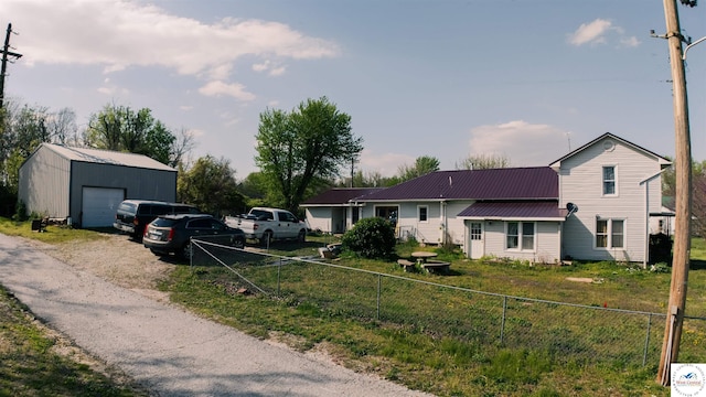 view of front of home with an outbuilding, metal roof, a garage, and fence