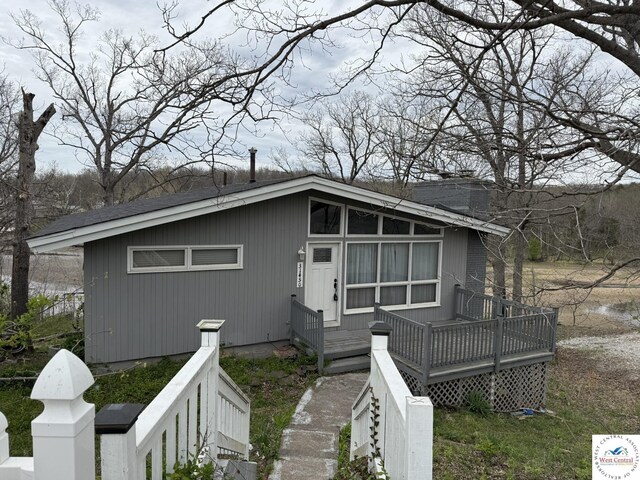 view of front of house with a deck and a shingled roof