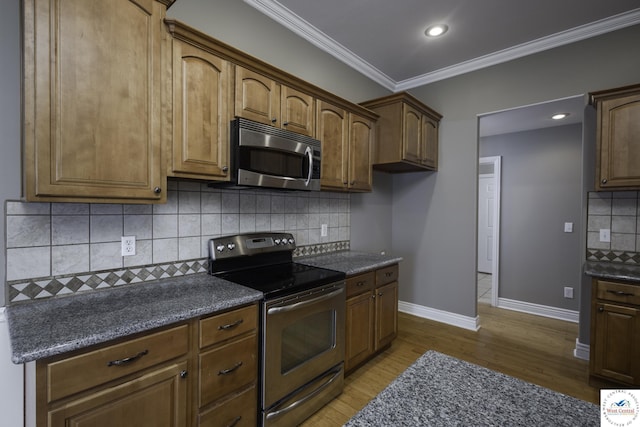 3415 Callaway Dr, Sedalia, MO 65301 - kitchen with appliances with stainless steel finishes, baseboards, wood finished floors, ornamental molding, and decorative backsplash