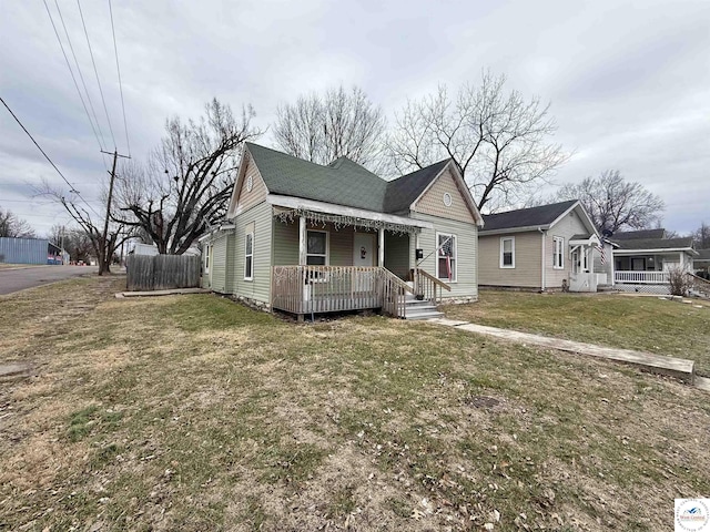 bungalow-style house with a porch, a front yard, and a shingled roof