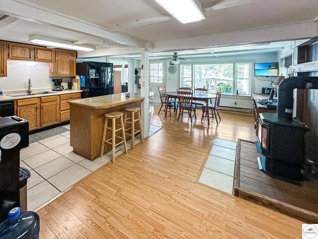 15157 Bass Rd, Gravois Mills, MO 65037 - kitchen with black fridge, a sink, a wood stove, light countertops, and a ceiling fan