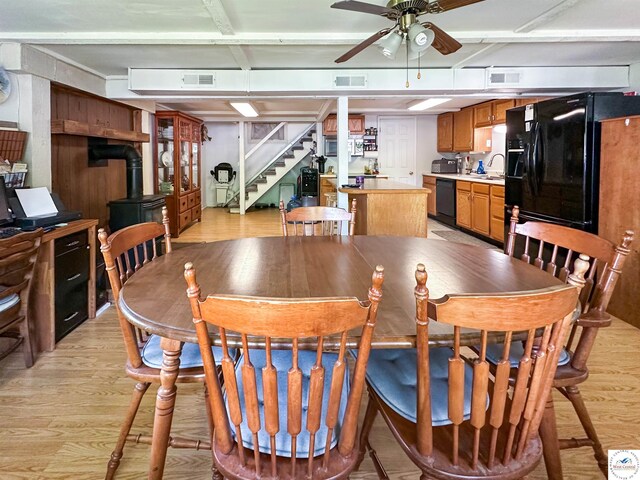15157 Bass Rd, Gravois Mills, MO 65037 - dining area with light wood finished floors, ceiling fan, a wood stove, and stairway