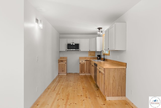 Gardiner Rd, Edwards, MO 65326 - kitchen featuring stainless steel appliances, a sink, light wood finished floors, light countertops, and white cabinets