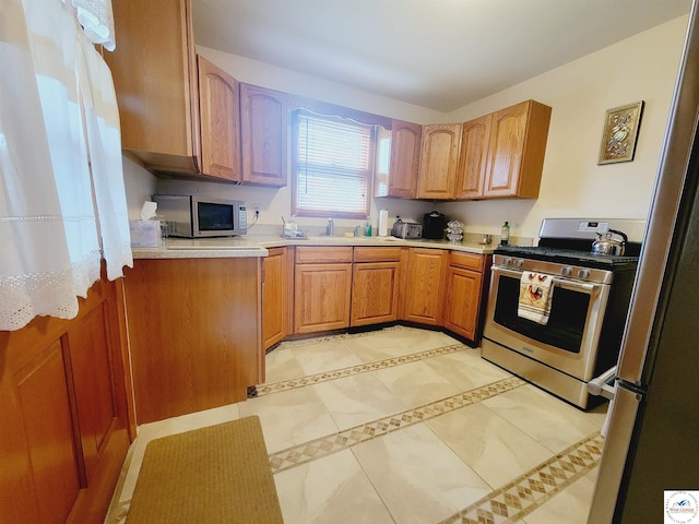 330 W State St, Tipton, MO 65081 - kitchen featuring light tile patterned floors, brown cabinets, a sink, appliances with stainless steel finishes, and light countertops