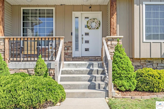 entrance to property featuring board and batten siding, covered porch, and stone siding