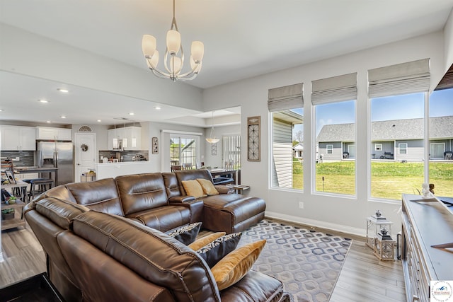 living room featuring recessed lighting, baseboards, an inviting chandelier, and wood finished floors