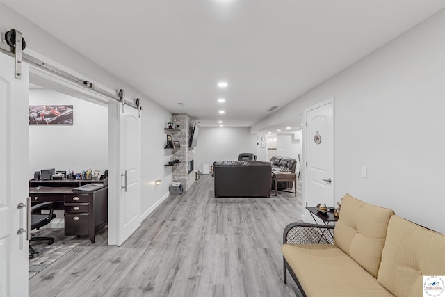 living area featuring a barn door, light wood-style floors, recessed lighting, baseboards, and visible vents
