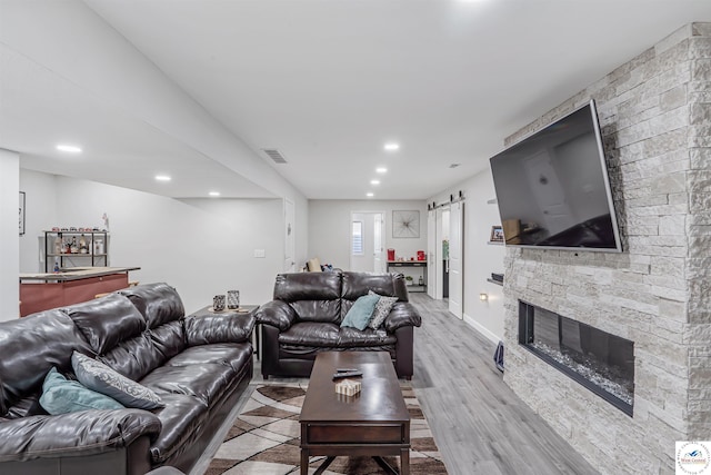 living room with visible vents, recessed lighting, light wood-style floors, and a barn door