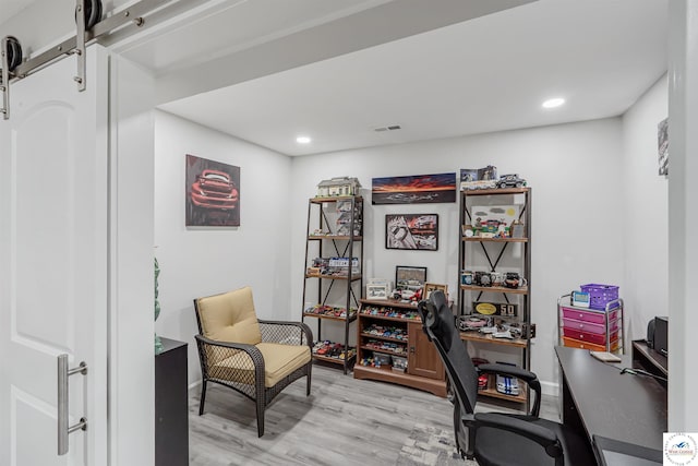 office area with recessed lighting, baseboards, a barn door, and light wood-style flooring