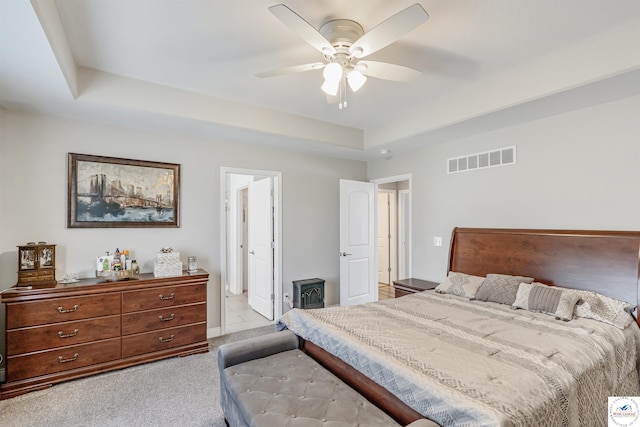 carpeted bedroom featuring visible vents, a ceiling fan, and a raised ceiling