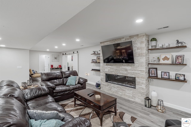 living area with visible vents, wood finished floors, baseboards, recessed lighting, and a barn door
