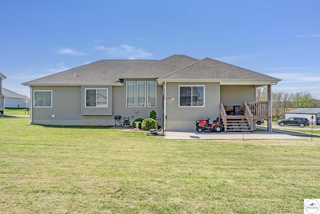 rear view of house featuring a patio, a shingled roof, and a yard