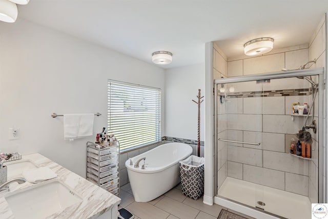 bathroom featuring a sink, tile patterned flooring, double vanity, a freestanding tub, and a stall shower